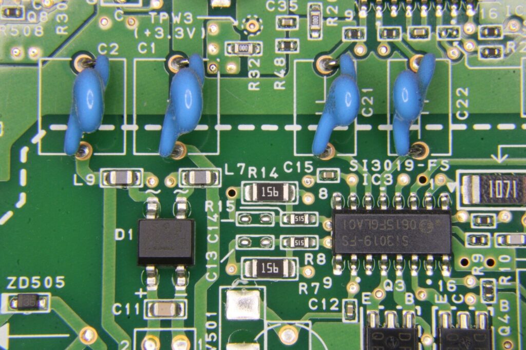 Green circuit board with chips, resistors, and blue capacitors