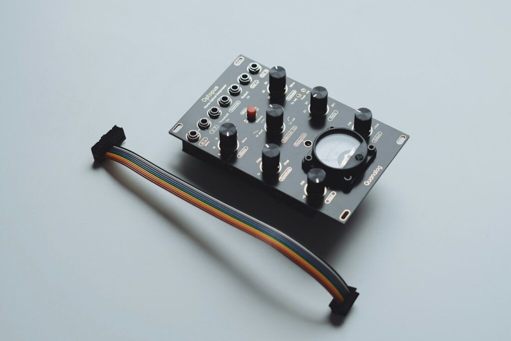 A black electronic module with knobs and a cable