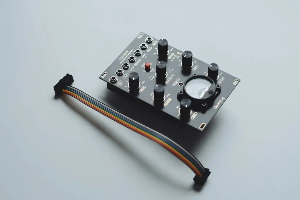 A black electronic module with knobs and a cable